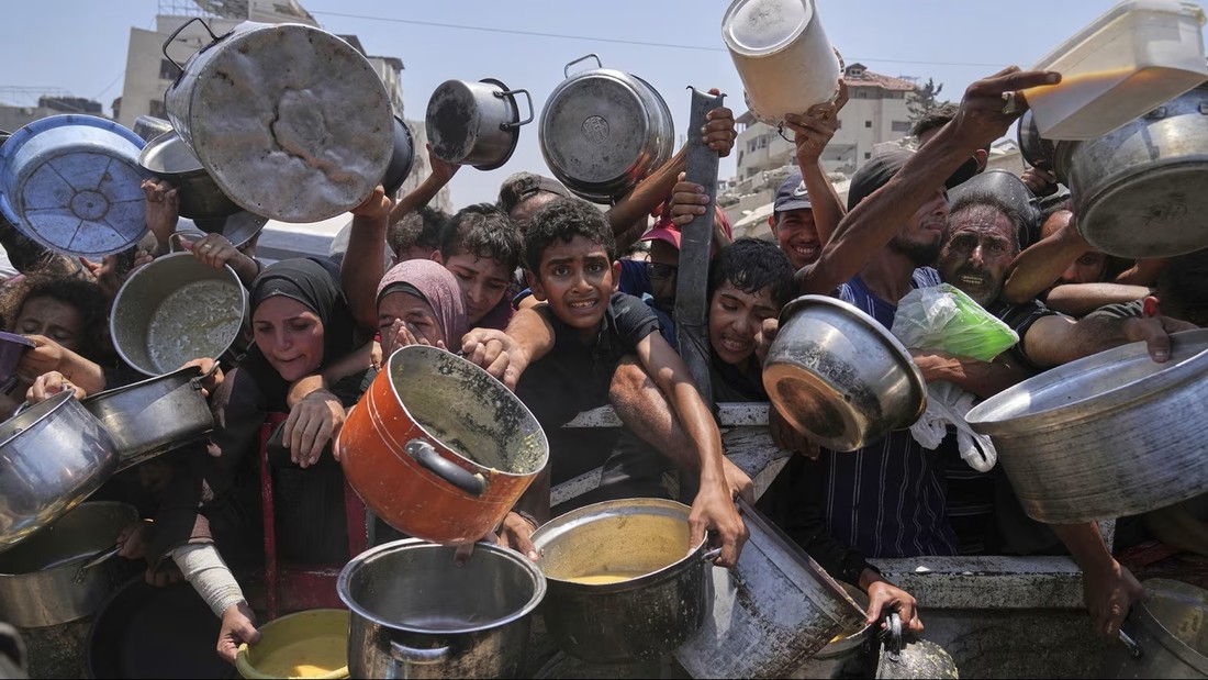Palestinians hold out pots and pans at a community kitchen in Gaza City on Saturday, July 26, 2025. Abdel Kareem Hana/AP
